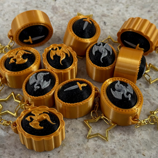 Gold framed fidget clickers with dragons or swords on a black background centerpieces on a textured surface