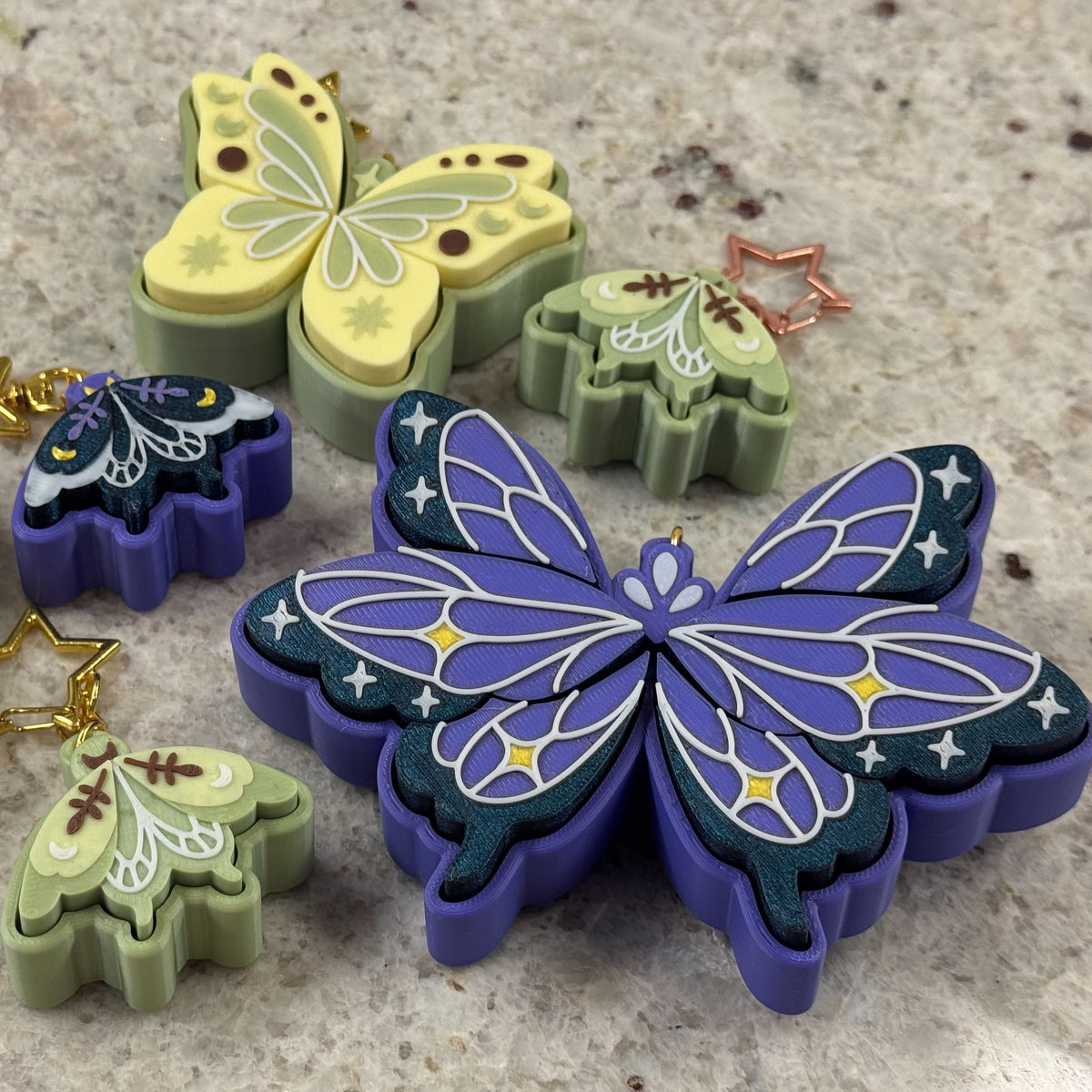 Collection of butterfly and moth fidget clickers of various sizes in green and purple